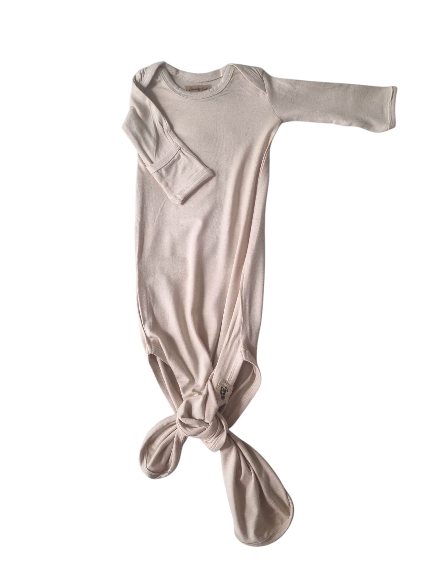 Baige Baby knotted gown, one sleeve pointing out to the right and on sleeve showing rolled sleeve, front view