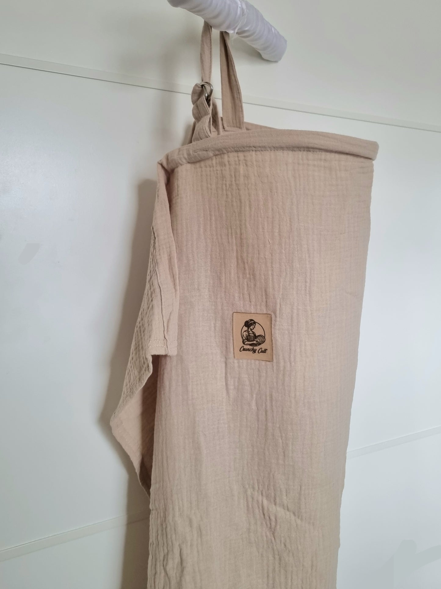 Baige breastfeeding cover, close-up view, showing the adjustable belt and logo