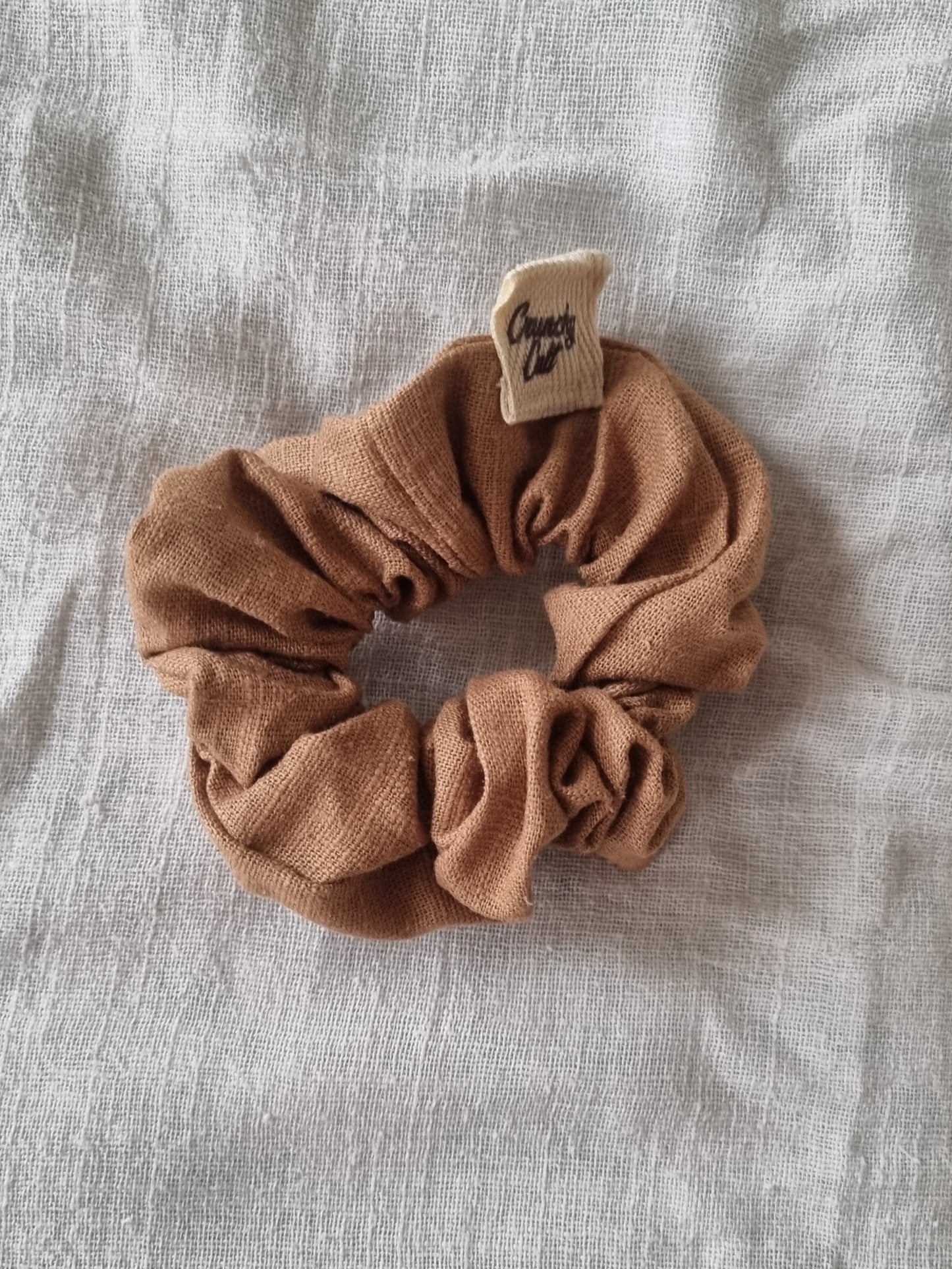 Brown linen hair scrunchy, single, top view, modelled on grey sheet