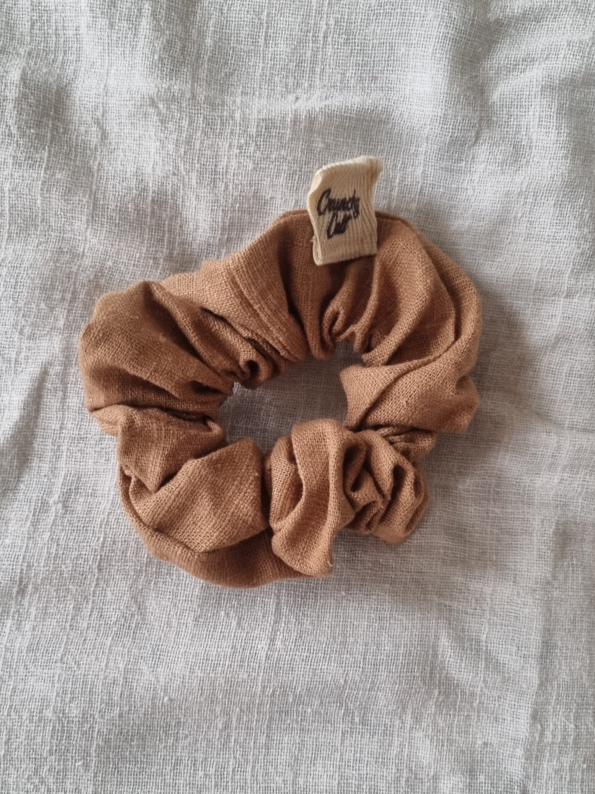Brown linen hair scrunchy, single, top view, modelled on grey sheet