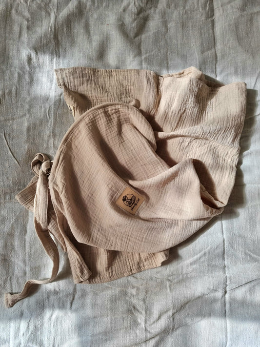 Baige breastfeeding cover, crunched up on table with linen sheet. Top view